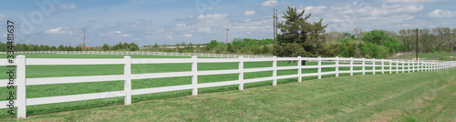 Panoramic long wooden white fence to horizontal line in cloud blue sky at farmland in Ennis, Texas, USA