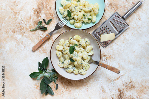 Italian homemade gnocchi with butter, cheese and sage served in two plates on a light marble table. Italian food. Copy space. Flat lay