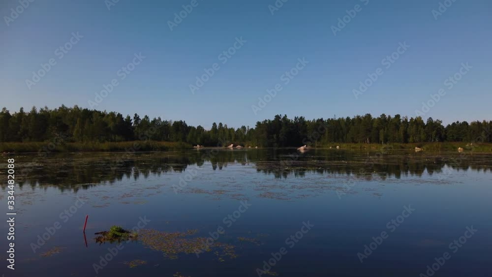 Blue sky and conifer forest mirrored on surface of still lake in Sweden Blue sky and conifer forest mirrored on surface of still lake in Sweden