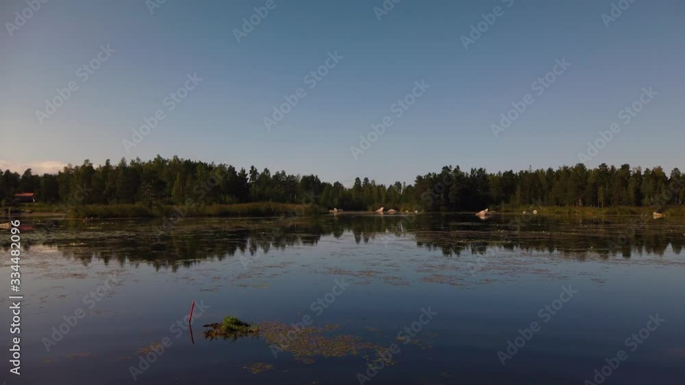 Dark blue evening sky and treeline mirrored on still lake in Sweden Dark blue evening sky and treeline mirrored on still lake in Sweden