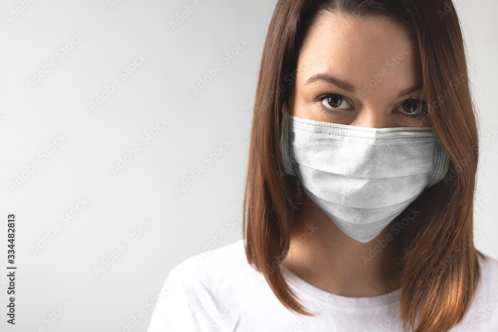 Coronavirus concept. Girl wearing a protective medical mask. Protect your health. Stop the virus and pandemic covid-19. Light gray background Coronavirus concept. Girl wearing a protective medical mask. Protect your health. Stop the virus and pandemic covid-19. Light gray background