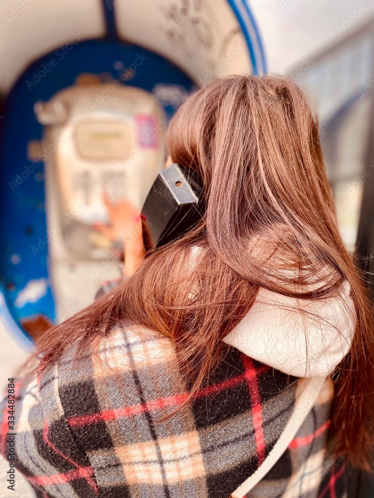 Fototapeta premium a girl in a protective mask near public phone during quarantine