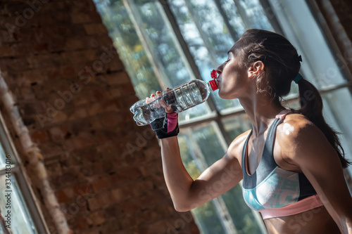 Thirsty dehydrated tired bodybuilder woman wear sportswear hold bottle drink fresh clean in gym, fit sporty young beautiful girl healthy lifestyle sport workout fitness training hydration concept photo
