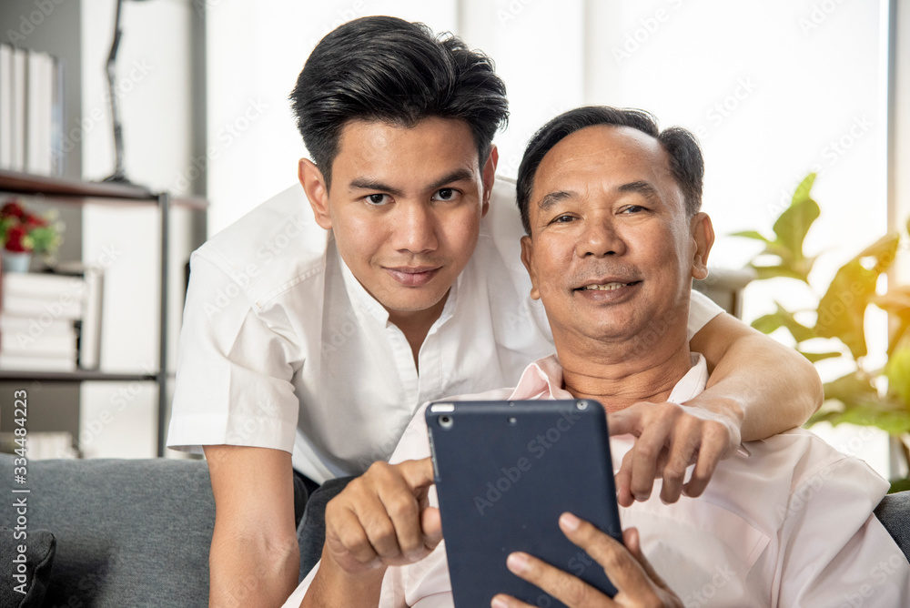 Senior Asian father and son are discussing the popular online business investment on smartphones. Warmly in the morning at home The concept of family life Senior Asian father and son are discussing the popular online business investment on smartphones. Warmly in the morning at home The concept of family life