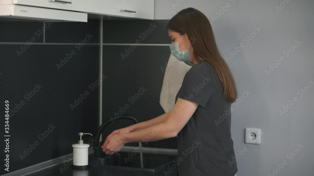 Woman in a medical mask washes her hands thoroughly, uses liquid soap for disinfection in COVID-19. Hygiene in quarantine of coronavirus, disinfection of hands to destroy microbes. Beautiful girl uses Woman in a medical mask washes her hands thoroughly, uses liquid soap for disinfection in COVID-19. Hygiene in quarantine of coronavirus, disinfection of hands to destroy microbes. Beautiful girl uses
