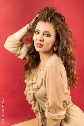 Portrait of beautiful young woman with perfect makeup. Fashion beauty portrait on red background.