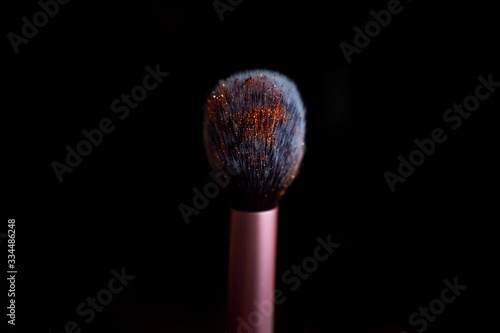 pink make up brush stanting up on dark isolated background studio shot