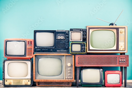 Retro classic TV receivers set from circa 60s, 70s and 80s, old wooden television stand with amplifier front mint blue wall background. Broadcasting, news concept. Vintage style filtered photo photo