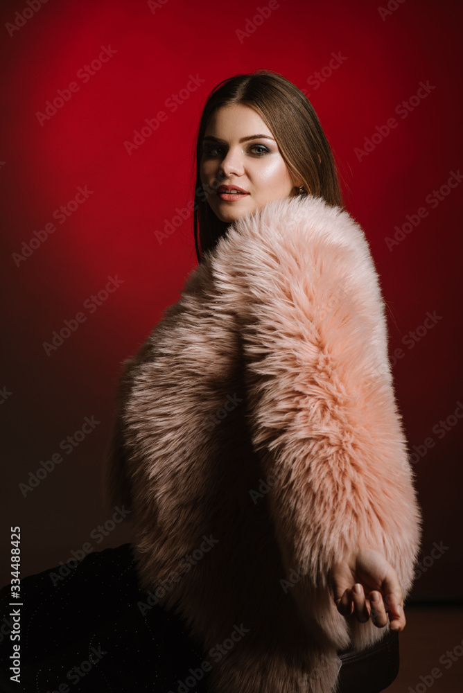 Fashion portrait of woman wearing a fur on black and red background Fashion portrait of woman wearing a fur on black and red background