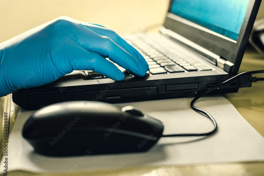 A man in blue rubber gloves is typing on the keyboard. work from home, the fight against the virus, coronavirus. A man in blue rubber gloves is typing on the keyboard. work from home, the fight against the virus, coronavirus.