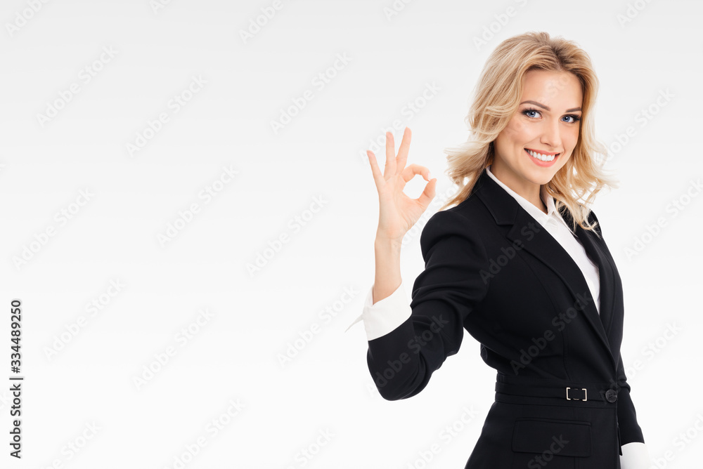 Happy smiling businesswoman showing okay gesture, on grey background, with blank copyspace area for slogan or text message. Caucasian blond model in business concept. Happy smiling businesswoman showing okay gesture, on grey background, with blank copyspace area for slogan or text message. Caucasian blond model in business concept.