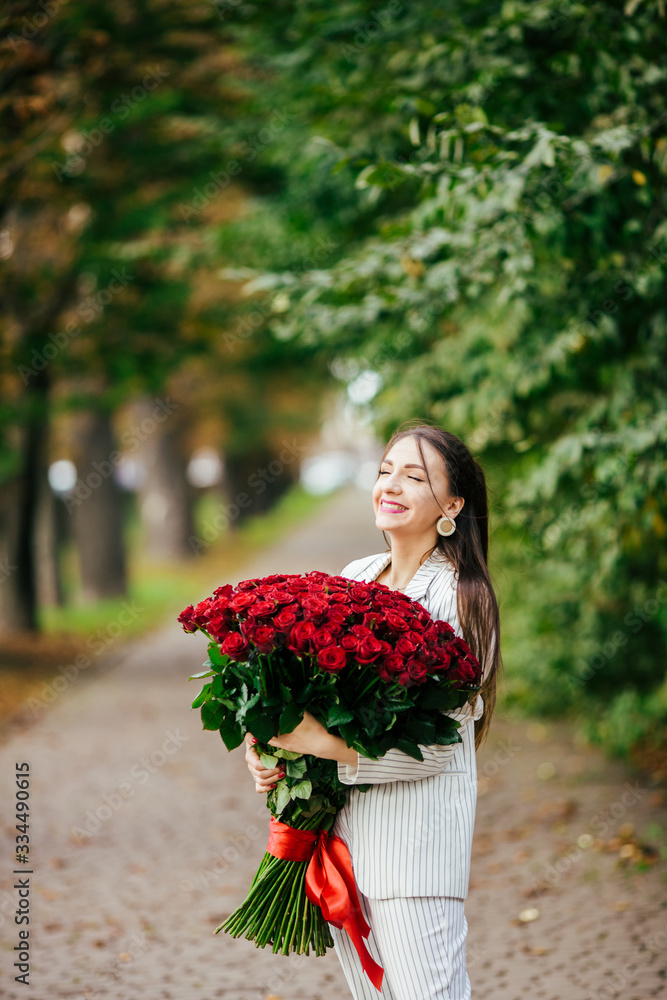 Fototapeta premium Smiling girl with bouquet of red roses