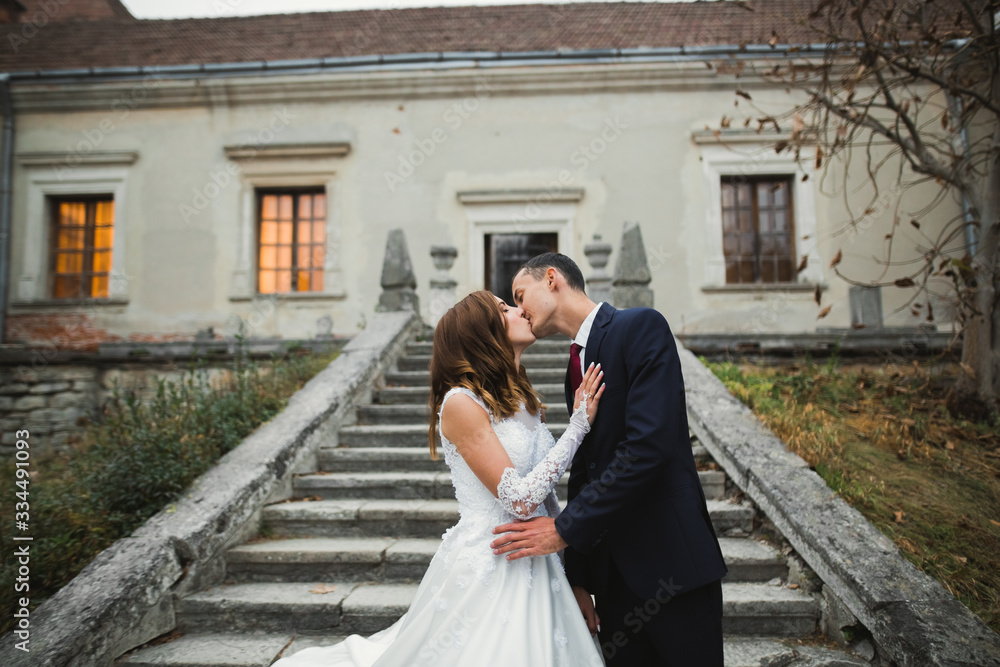 Beautiful bride and groom embracing and kissing on their wedding day Beautiful bride and groom embracing and kissing on their wedding day