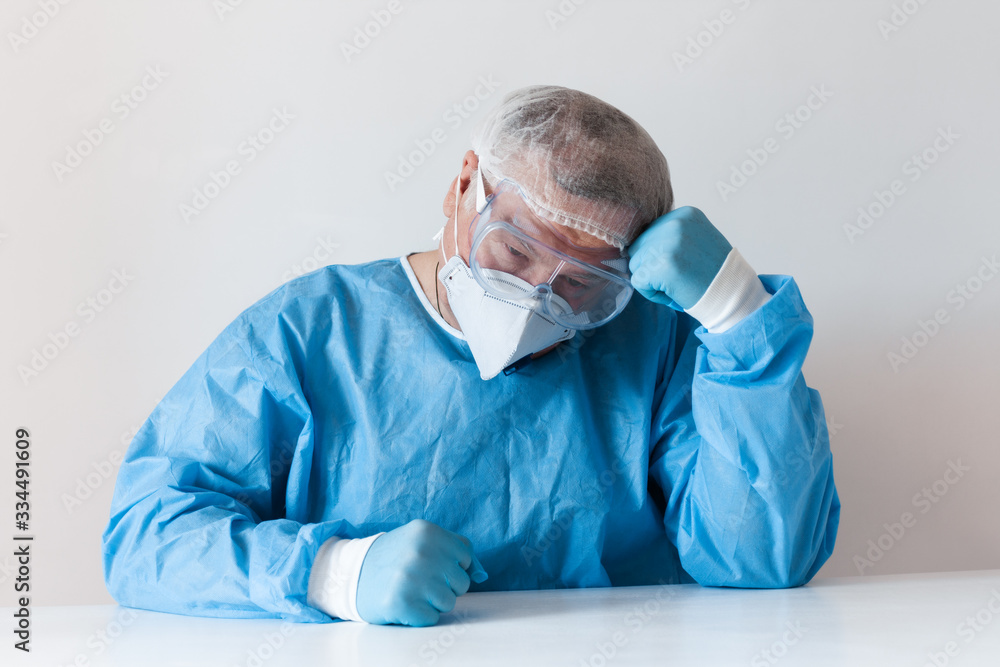 Coronavirus Covid-19 concept. Tired elderly doctor in glasses and a respirator mask for protection after hard work in hospital. Wuhan, China epidemic virus Cov-19 symptoms quarantine background.