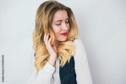 portrait of young blond beautiful woman with red lips wearing smart suit stands on isolated white background, looks sexy , style and beauty concept