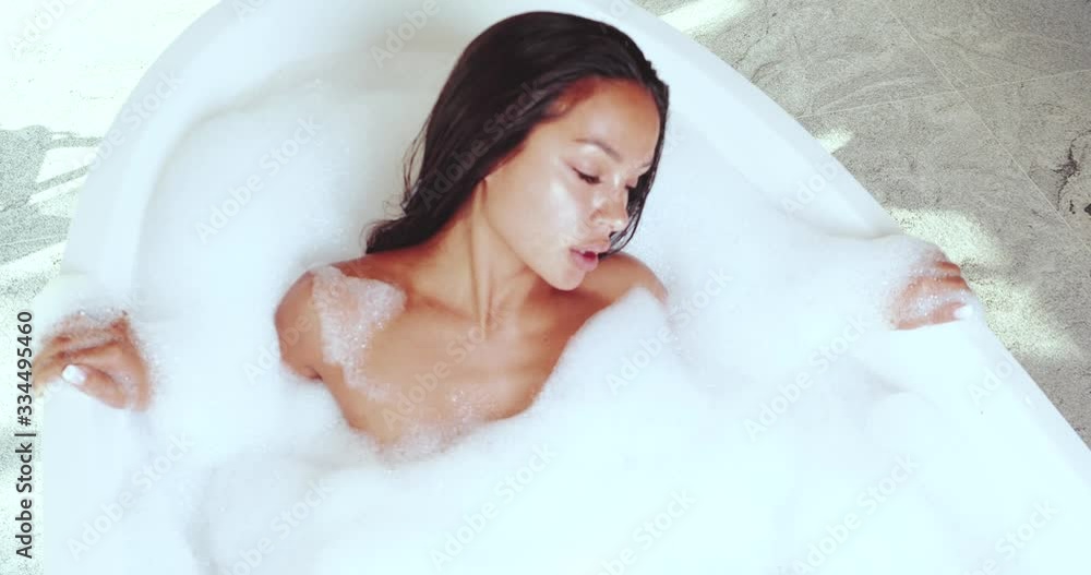 Top view of beautiful and sensual brunette woman relaxing in bathtub with foam - video in slow motion Top view of beautiful and sensual brunette woman relaxing in bathtub with foam - video in slow motion