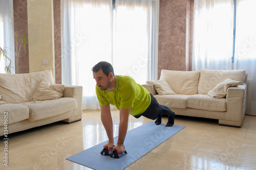 Bearded man in low shape exercising with black and green sportswear