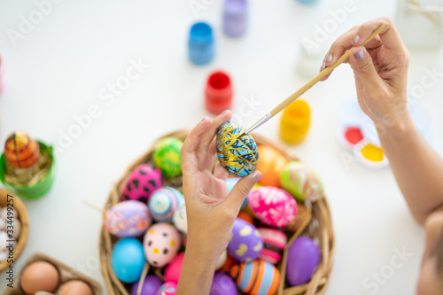 Asian young pretty woman enjoy painting a water colors on fantasy eggs for Easter egg festival. Beautiful colorful fancy Easter egg in bucket. The symbolic of Easter egg festival concept.