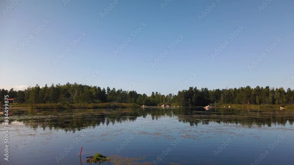 Static view of still lake by forest under clear blue sky in Sweden Static view of still lake by forest under clear blue sky in Sweden