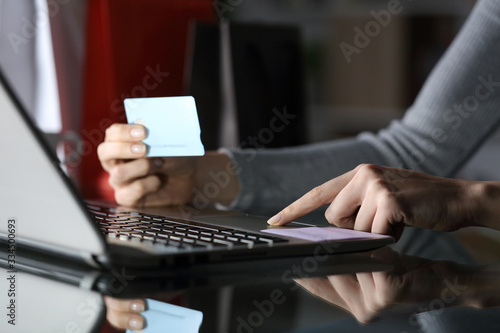Woman paying on laptop with credit card at night