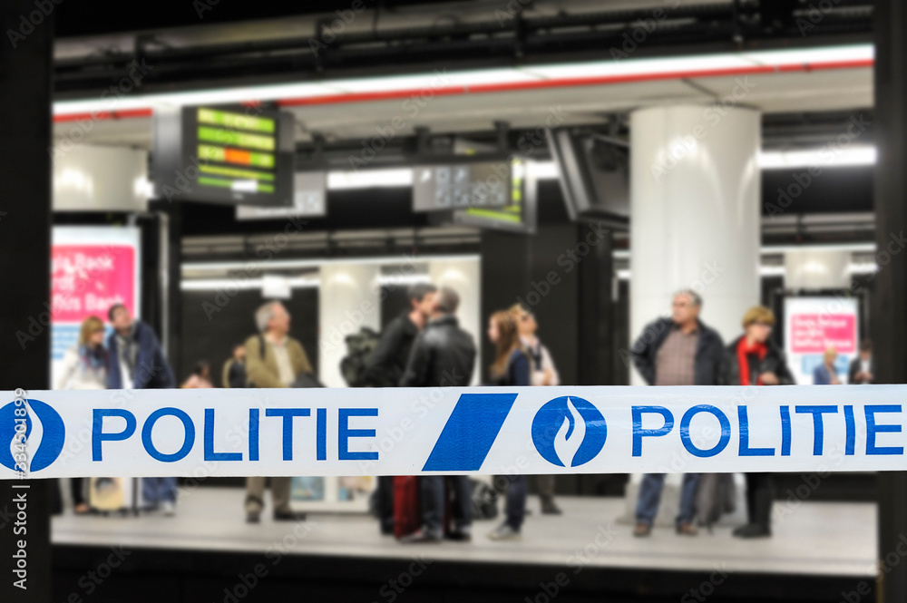 Politie / police tape in front of commuters waiting for train at platform of Belgian railway station in Belgium