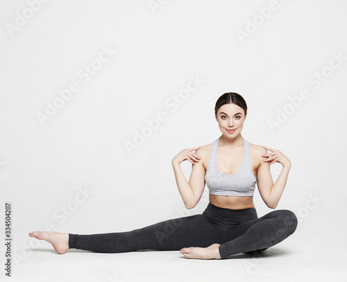 Young woman practicing yoga, working out, wearing sportswear, studio shoot over white background