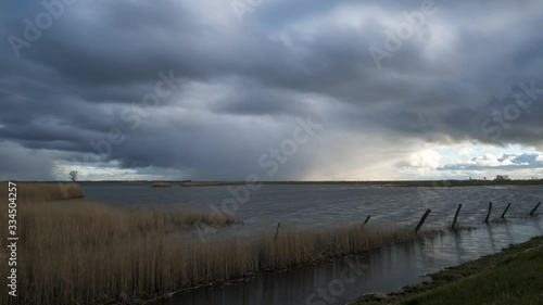 Time lapse of dramatic rain cloud rolling in with a moor and reeds in the forground