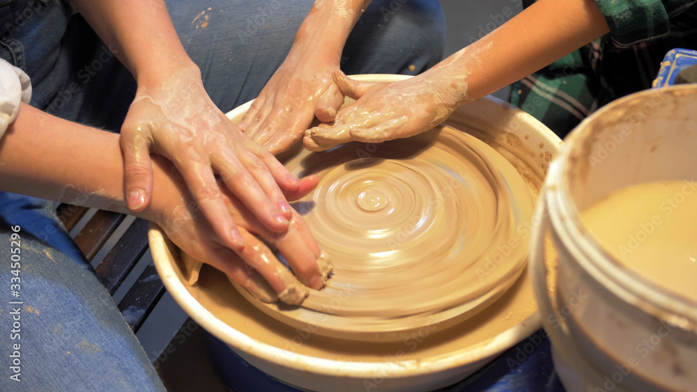 Woman and boy make plate on pottery wheel in workshop Woman and boy make plate on pottery wheel in workshop