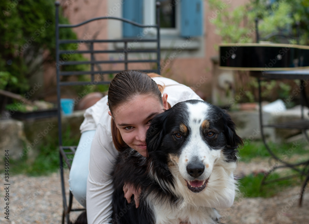 smiling Teenage girl hugging dog in garden.