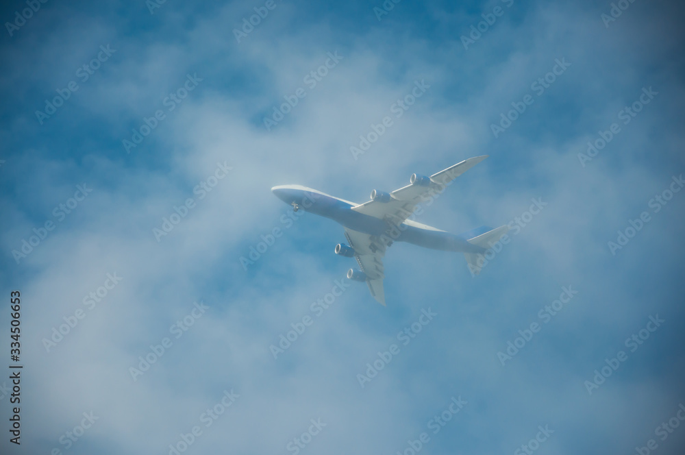 Flying plane in the blue, cloudy sky.