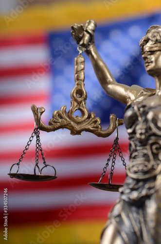 Scales of Justice, Justitia, Lady Justice in front of the American flag in the background.