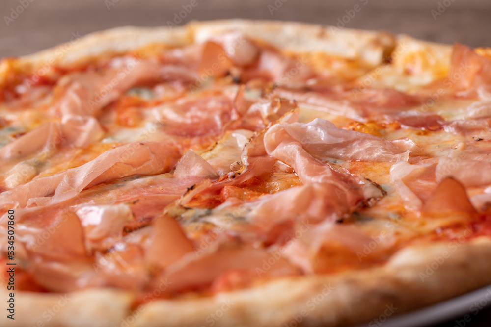 details of fresh baked pizza with ham on a wooden table details of fresh baked pizza with ham on a wooden table