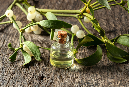 Fotografiet A bottle of essential oil with fresh mistletoe in the background