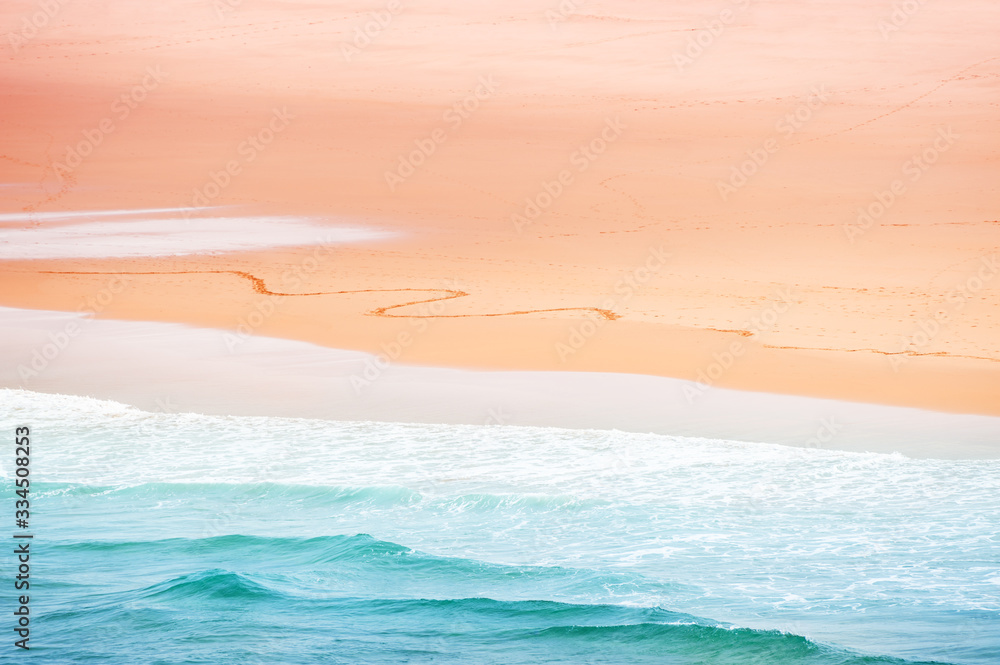 Beautiful shore of Atlantic ocean in Algarve, Portugal. Blue water with pink sand. Abstract sea background