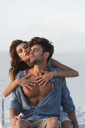 passionate young woman touching boyfriend torso on beach