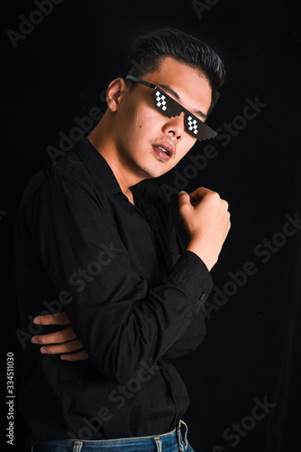 Handsome young man in black shirt keeping arms crossed wear glasses on black background , Asia Portrait