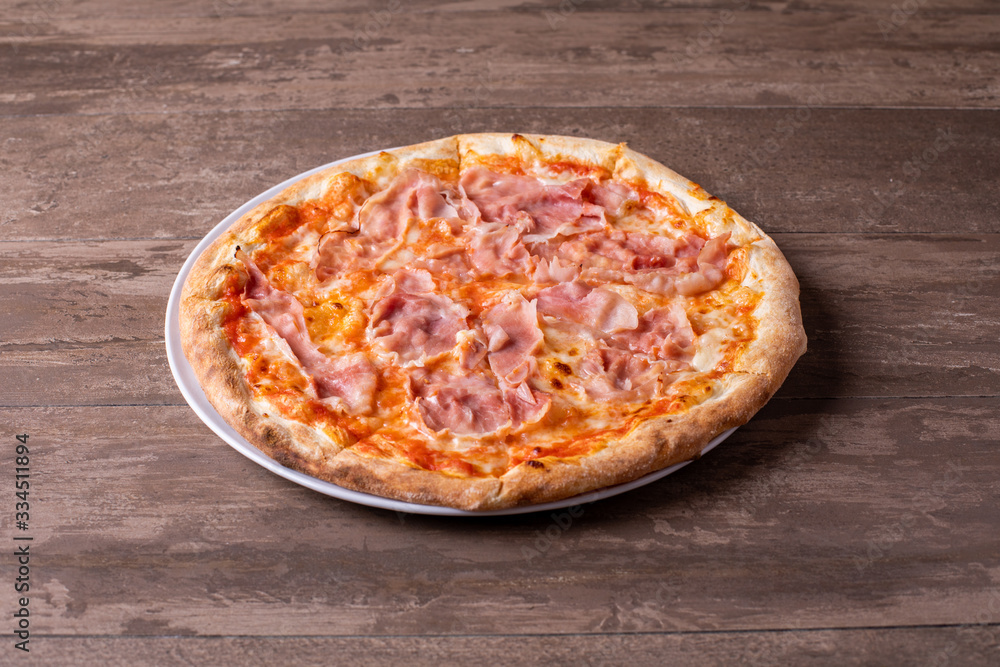details of pizza with mozzarella and ham on a wooden background details of pizza with mozzarella and ham on a wooden background