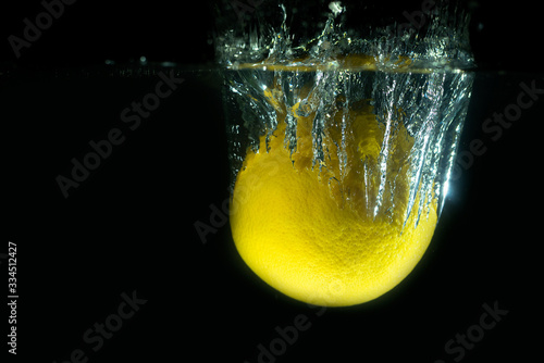Lemon dropping in water Lemon with water splash underwater food photograph with black background