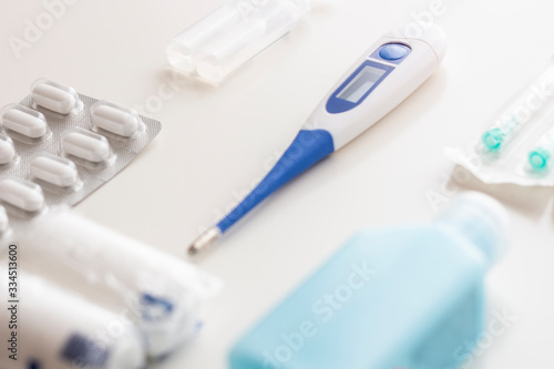 Medical supplies kit for health emergencies, consisting of thermometer, bandages, analgesics, antiseptics, serum, hand sanitizer, needles and syringe, on white background, selective focus