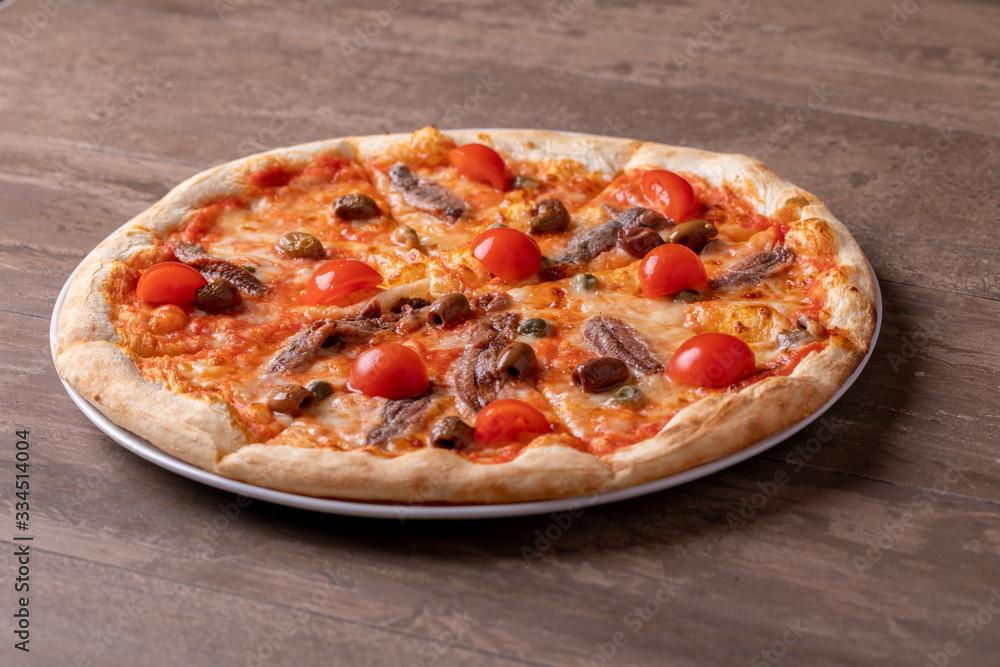 Close up of tasty hot pizza with anchovies and tomatos
