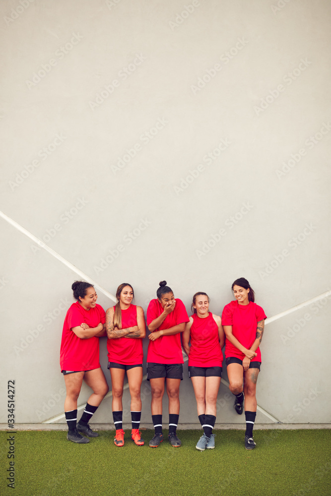 Obraz premium Graphic Shot Of Womens Football Team Leaning Against Wall Whilst Training For Soccer Match