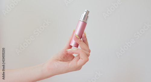 young woman holding a bottle of perfume in hand. metal bottle with spray on a white. cosmetology beauty pattern.