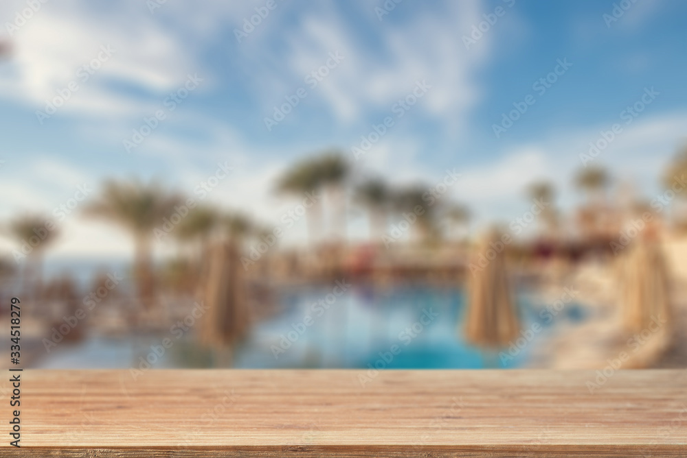 Empty tabletop against the backdrop of a swimming pool, palm trees and sea beach