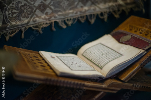 Quran islamic holy book on dark background with with blurred traditional carpet for reading in ramadan night