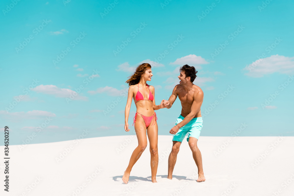 smiling young couple holding hands on sandy beach smiling young couple holding hands on sandy beach