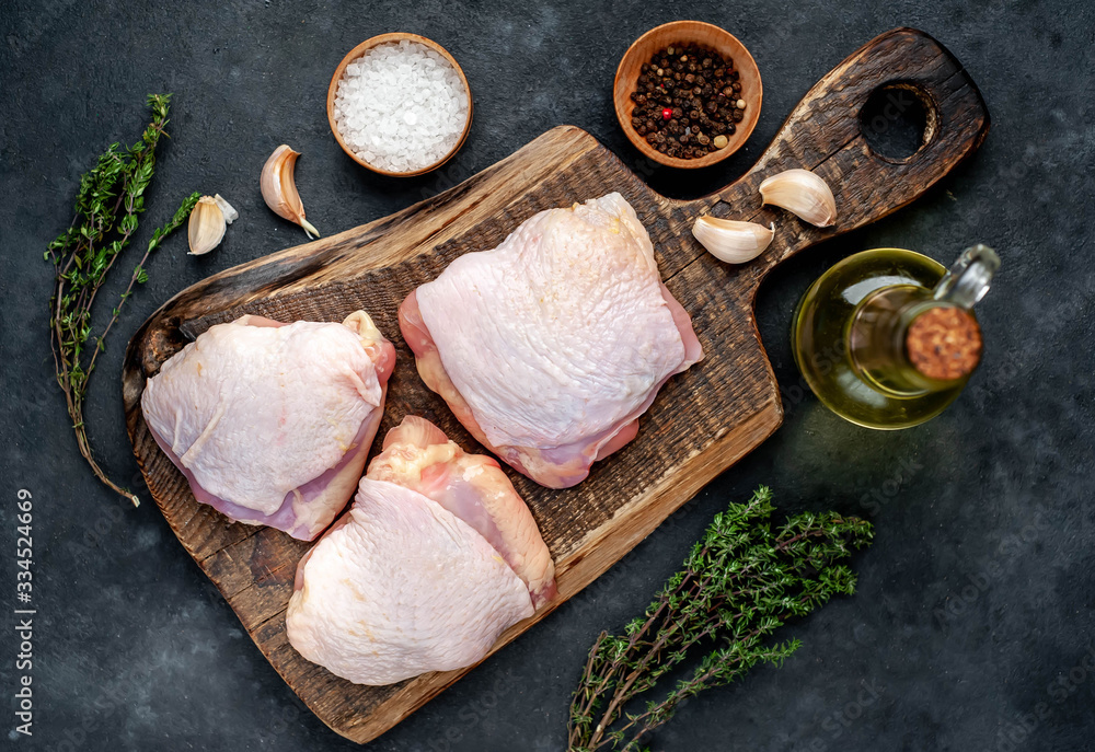 Raw chicken thighs with spices on a stone background - obrazy, fototapety, plakaty 