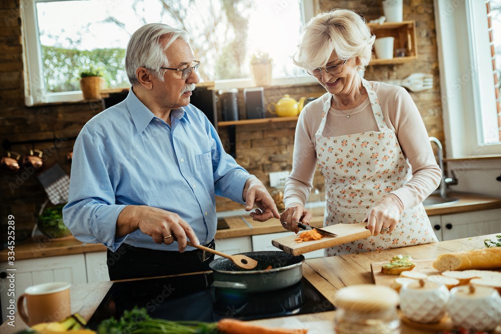 Senior couple enjoying while preparing meal together in the kitchen. Senior couple enjoying while preparing meal together in the kitchen.