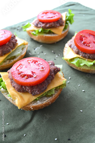 burger rolls with sesame seeds with lettuce, cheese, meat cutlet and tomato