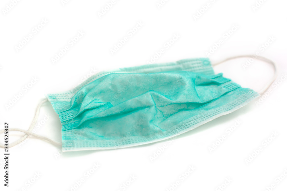 Green disposable face mask with ear straps. Typical 3-ply surgical mask to cover the mouth and nose. Virus protection concept. Green disposable face mask with ear straps. Typical 3-ply surgical mask to cover the mouth and nose. Virus protection concept.