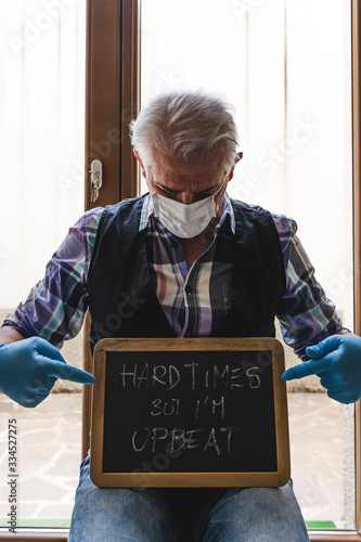 single mature man quarantined by coronavirus at window shows a message